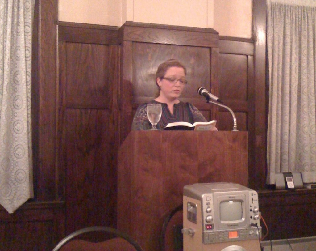 Katrina Reading "Table for Six" at a Podium
